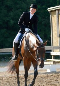 Woman in English gear riding horse for dressage.